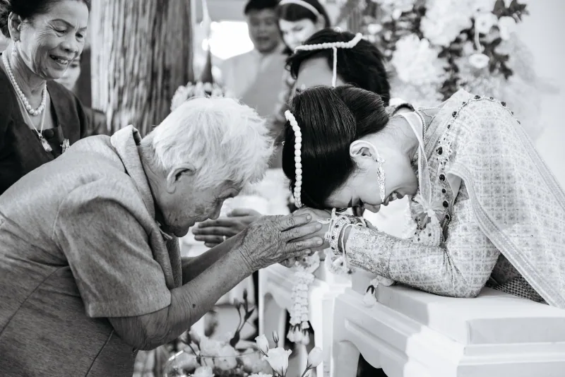 ภาพขาวดำของผู้ใหญ่ก้มอวยพรคู่บ่าวสาวในพิธีแต่งงาน